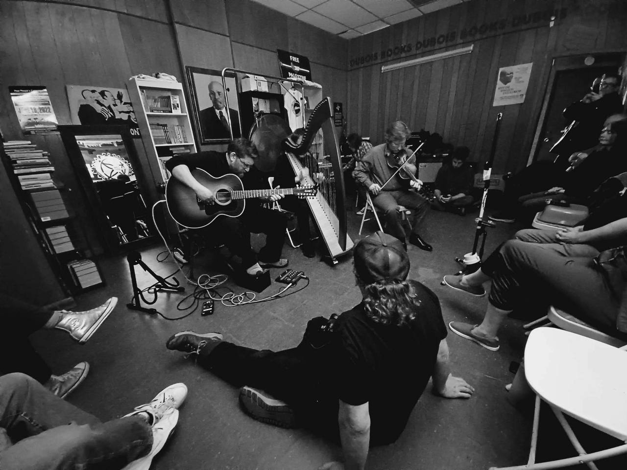 Black and white photo of people sitting around a room while a band plays